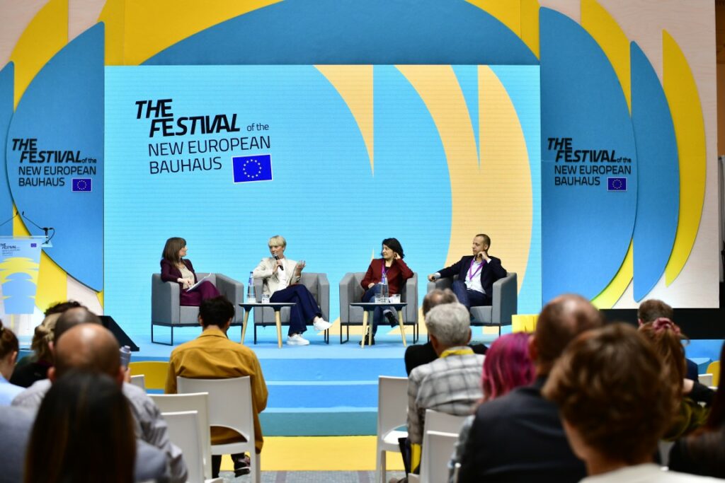 Four speakers participating in a panel discussion during a plenary session at NEB 2026